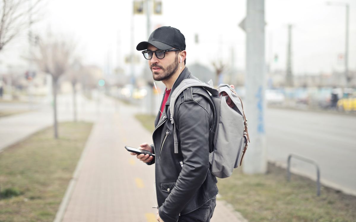 Divatos fiatal férfi Budapesten, telefonját nézi egy forgalmas utcán