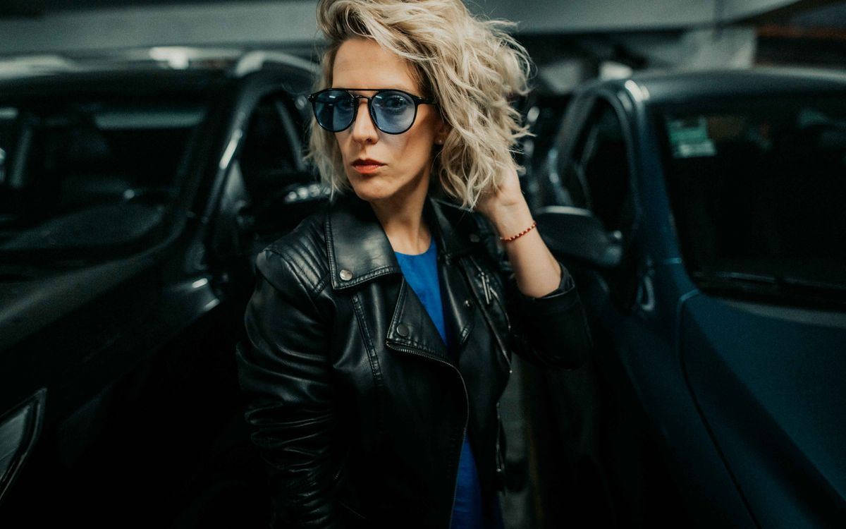 Elegáns nő bőrkabátban, magabiztosan pózolva városi környezetben