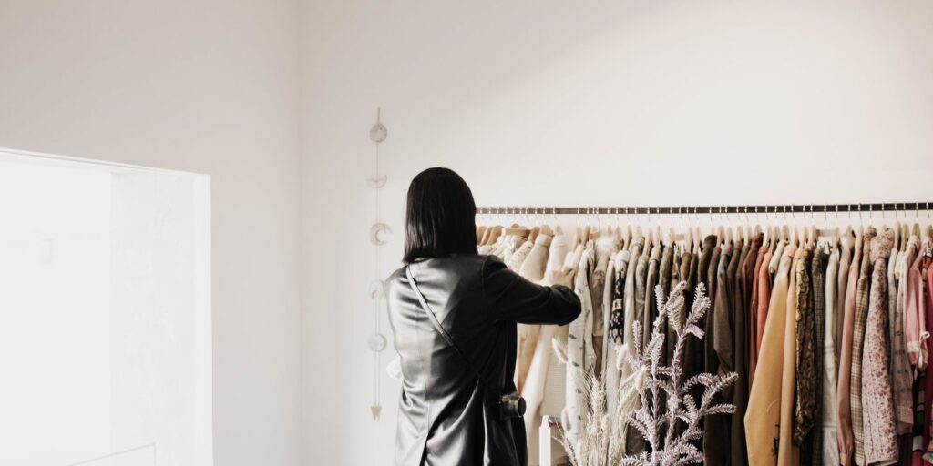 Egy nő bőrkabátokat néz egy elegáns, fényes butik ruhaállványán