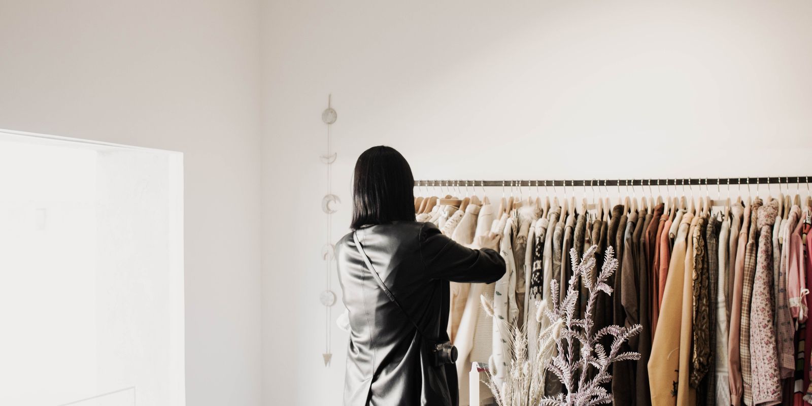 Egy nő bőrkabátokat néz egy elegáns, fényes butik ruhaállványán