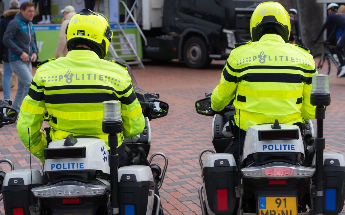 Két rendőr világos egyenruhában motorral járőrözik egy közösségi eseményen