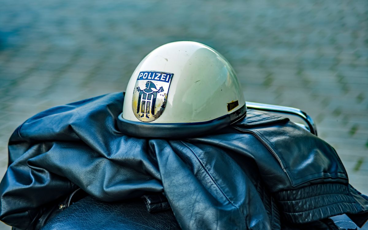 Retró rendőrsisak jelvénnyel egy bőrkabáton pihenve, kültéren
