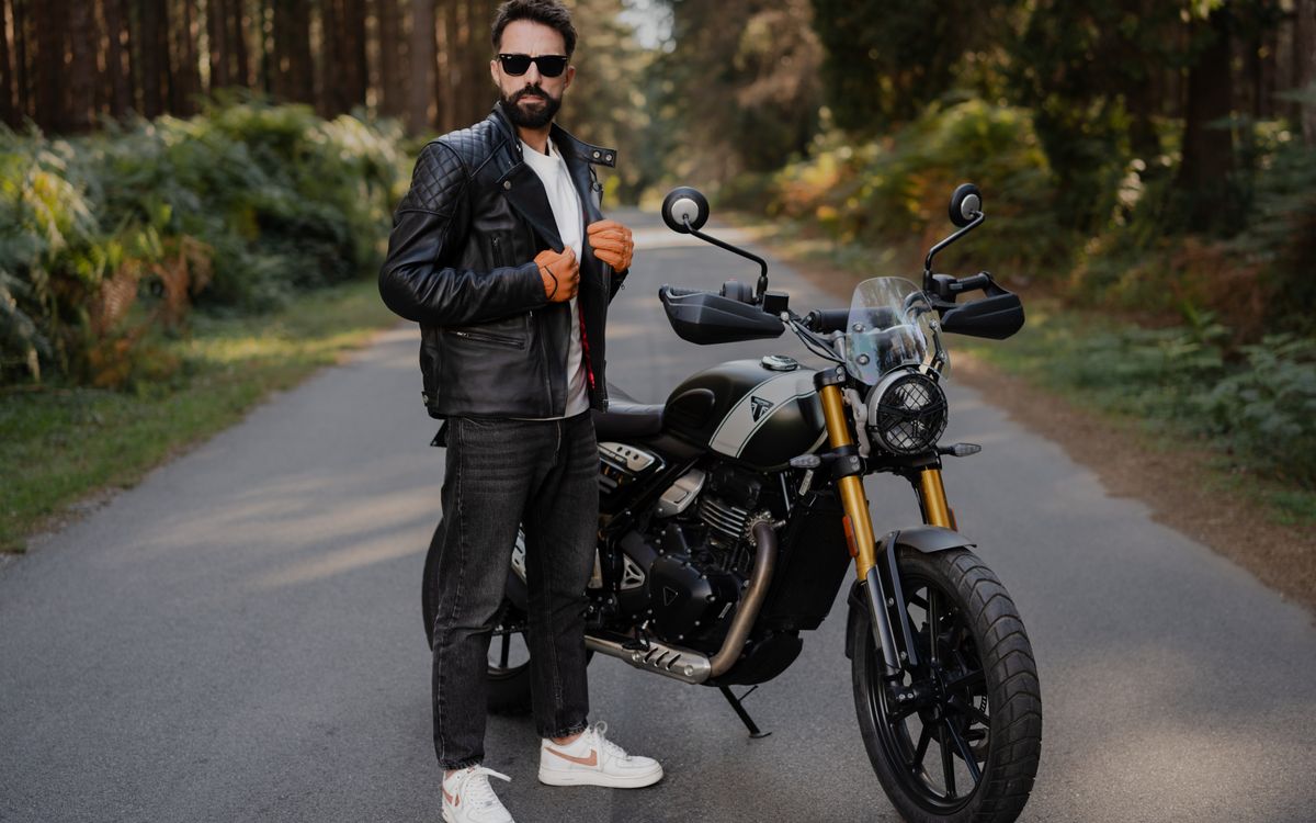 Elegáns férfi motorral pózol egy nyílt úton